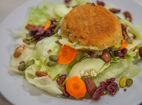 Ensalada con lechuga pepino zanahoria, granos y semillas, sobre una mesa, con croqueta de papa encima, estilo de vida y concepto de comida saludable.
