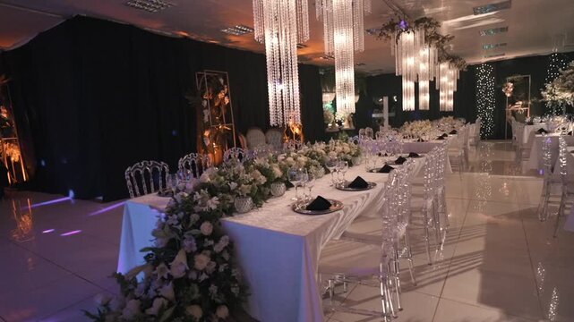 An opulent wedding banquet table features a cascading flower runner and grand crystal chandeliers.