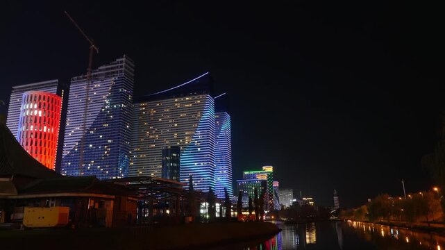 Timelapse of evening illumination of modern skyscrapers in Batumi at night. Glowing Batumi panorama with modern hotels and city pond. Capital of Adjara