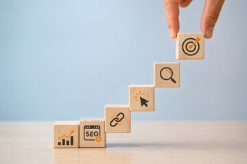 Konsep tangga kesuksesan pemasaran digital. Tangan menyusun blok kayu dengan ikon SEO lalu lintas web dan target audiens untuk pertumbuhan bisnis.