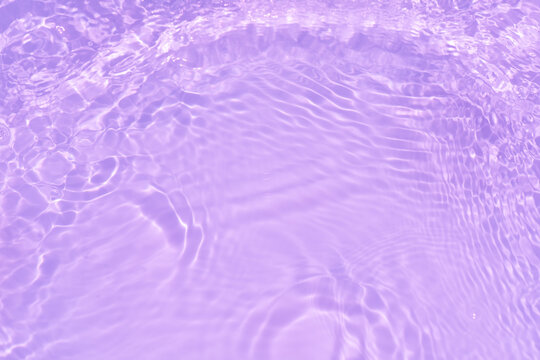 Pink water bubbles on the surface ripples. Defocus blurred transparent pink colored clear calm water surface texture with splash and bubbles. Water waves with shining pattern texture background