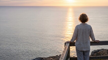 Fototapeta premium Woman enjoying the beautiful sunset over the calm ocean from a scenic viewpoint.