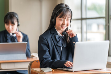 Fototapeta premium Elementary, middle, and high school girls in school uniforms using computers for lessons.
