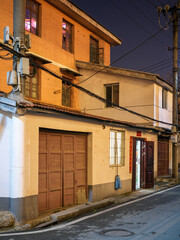 Fototapeta premium Old traditional residential building illuminated on narrow city street at night