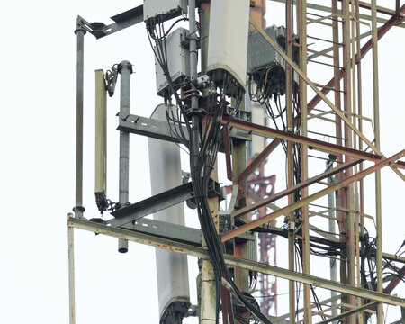 Closeup cellular tower infrastructure with sector panel antenna, remote radio unit, feeder cable, mounting bracket and lattice mast telecommunication equipment isolated background