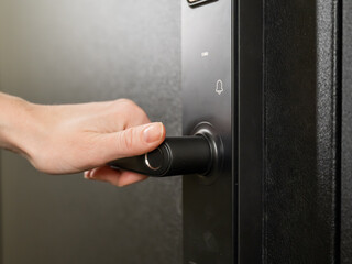 Naklejka premium A woman opens a modern smart door lock with a digital keypad and biometric fingerprint access.