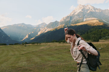 Naklejka premium Active woman hiking in a mountain valley with a backpack, sunlight on the landscape, outdoors, travel, fitness, nature, adventure, and exploration in a bright, fresh scene.