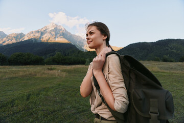 Naklejka premium Woman with backpack hiking outdoors in a mountain meadow, exuding confidence and curiosity. Concept of travel, exploration, wellness, and nature in warm daylight, soft glow.