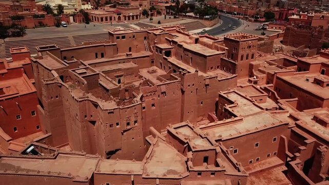 Aerial view of traditional kasbah buildings blending with modern infrastructure in Ouarzazate, Morocco. Contrast between historic adobe architecture and contemporary urban elements, ideal for culture,
