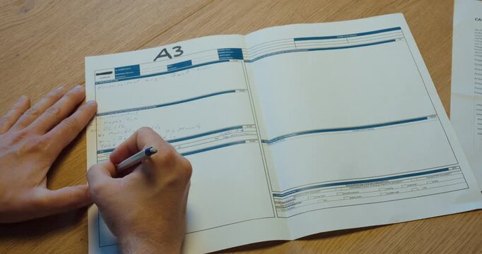 Person writing on an A3 report sheet, representing structured problem solving, root cause analysis, and continuous improvement.