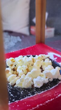 freshly popped corn sitting in a black bowl inside a red popcorn machine. This high-detail footage captures the texture of the snack in a movie theater setting.