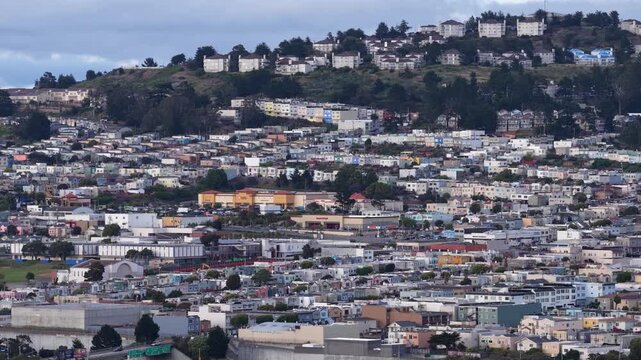 Aerial view of Daly City reveals rows of residential homes set along rolling hills, with coastal fog drifting through streets and rooftops in a quiet Northern California setting