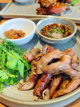 Golden-brown grilled pork chitterlings served hot with authentic Thai spicy dipping sauces and fresh local herbs, capturing the rustic essence of traditional Southeast Asian culinary art.