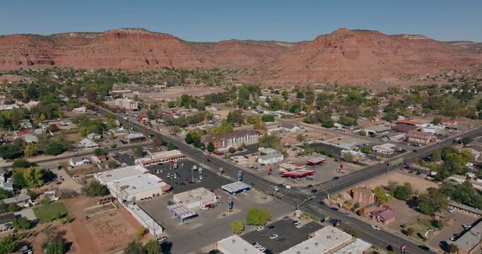 Kanab Utah streets and homes beneath red desert mesa formations, aerial drone background