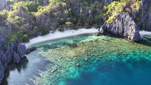 A scenic, secluded beach is surrounded by rugged, karst limestone in El Nido. This area in the Philippines is a popular vacation destination due to its coral reefs, beaches, and hidden lagoons.
