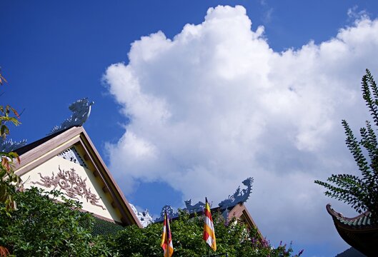 Intricate Dragon Statues on Traditional Buddhist Temple Roof Against Blue Sky