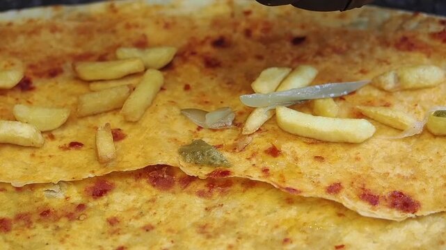 Chef Adding Sliced Pickles to a Flatbread Wrap with French Fries