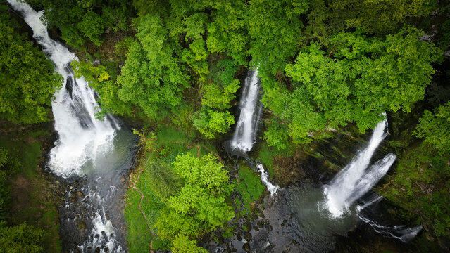 Aerial view of the Cascades du Flumen waterfalls cascading through a lush green forest into rocky pools in Septmoncel Les Molunes, Bourgogne-Franche-Comte, France.