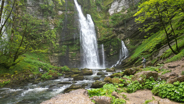 Aerial view of Cascades du Flumen waterfall cascading down rocky cliffs into a stream surrounded by lush green forest in Septmoncel Les Molunes, Bourgogne-Franche-Com, France.