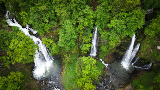Aerial view of Cascades du Flumen with multiple waterfalls plunging into rocky pools surrounded by dense green forest in Septmoncel Les Molunes, Bourgogne-Franche-Comte, France.
