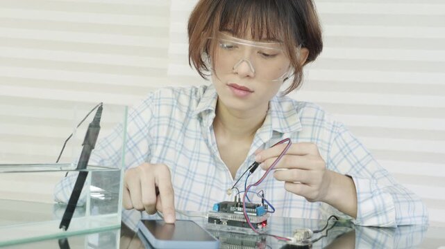 Woman is connecting the oxygen meter connector to the microcontroller and displaying the results on smartphone screen.