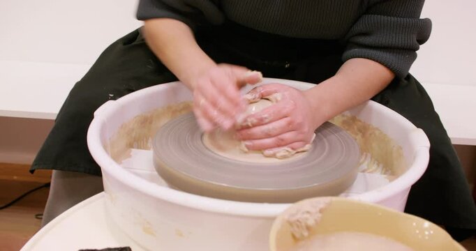 Artisan occupation. Hands clay forming. Unrecognizable professional woman master shaping raw for crockery craft using wheel in ceramic workshop.