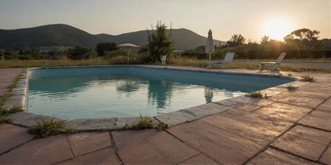 Fototapeta premium A serene rural pool scene at sunset, reflecting the warm golden light on a peaceful summer evening amidst rolling hills and distant mountains.