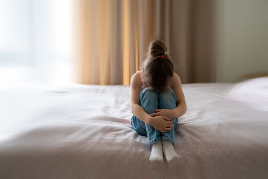 A little sad girl sitting on a bed with motion blur effect
