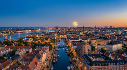Fototapeta premium Panoramic aerial view of Copenhagen canals and cityscape at dusk with a full moon rising.