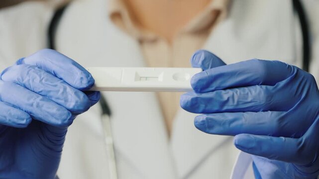 Doctor in medical gloves holding rapid antigen test kit for viral infection diagnostics in hospital.