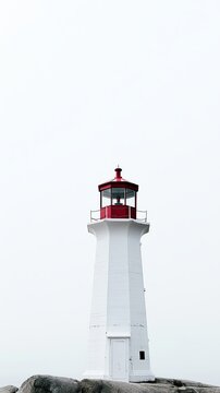 A solitary lighthouse stands amidst foggy skies.