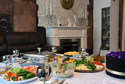 Servierter Tisch mit Obstplatte und Salaten und weisser Kamin im Hintergrung