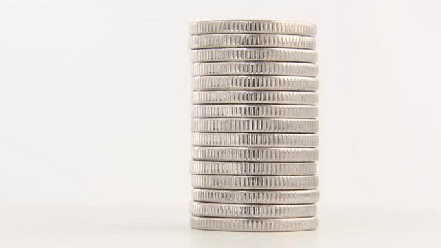 A tall stack of silver coins remains centered on a white background while the column slowly rotates with subtle movement, presenting stability, savings security and long term investment value.
