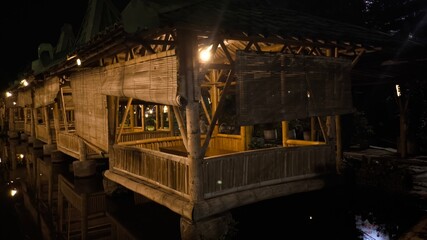 Obraz premium Serene bamboo structure corridor in tropical eco resort illuminated by warm lights at night, elegant wooden architecture, peaceful retreat ambience and relaxing travel scene