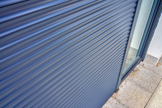 Closed roller shutter on glass door outside modern home