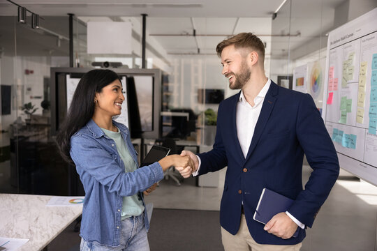 Two professionals exchange handshake, expressing mutual respect stand in modern office, gesture as symbol of successful collaboration completion, start partnership, or conclusion of business agreement