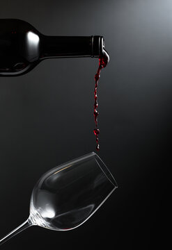 Red wine of rich color being poured from a bottle into a glass.