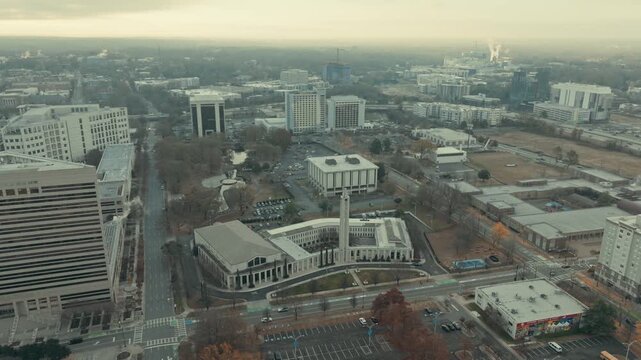 Aerial parallax circles First Baptist Church of Charlotte North Carolina, revealing neoclassical white facade, colonnaded wings and clock tower amid Uptown buildings on a grey winter day