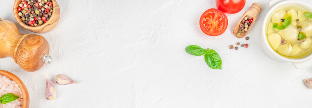 Cooking ingredients border with garlic, spices and basil on light background