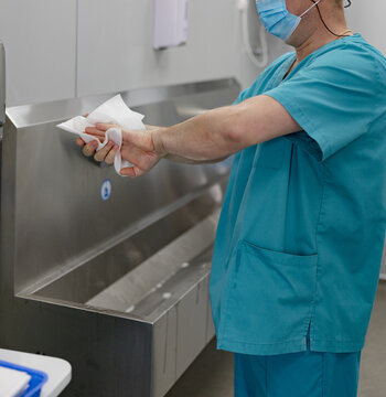 Surgeon drying hands with paper towel after washing in hospital