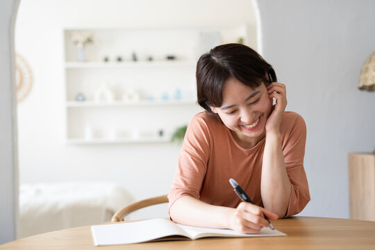 ノートに何かを書いているショートカットの女性