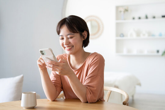家でスマホを見ながら笑っているショートカットの女性