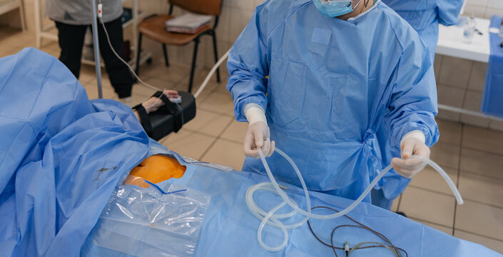 Professional surgeon performing operation with medical tubes in hospital