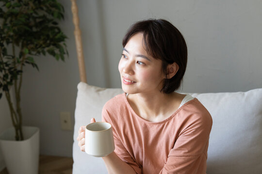 リビングでカップを持って笑っているショートカットの女性