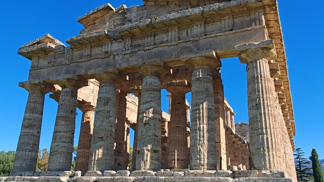 Ancient Greek Temple of Athena in Paestum, Italy at sunny day with blue sky. Famous archaeological site of Paestum, Magna Graecia, ancient ruins.