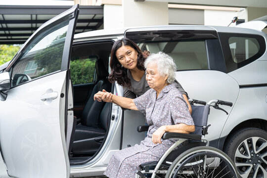 Caregiver help and support asian elderly woman sitting on wheelchair prepare get to her car to travel in holiday.