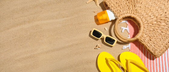 Obraz premium Composition with bottle of sunscreen cream, seashells and beach accessories on sand as background, closeup