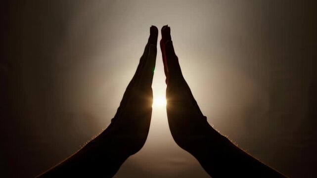 Silhouette of hands pressed together in a prayer or Namaste gesture