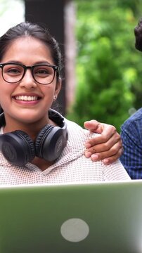 Indian students enjoying their free time on college grounds as they laugh heartily at funny quotes and jokes while using laptops and sharing books in a lively atmosphere