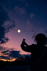 Fototapeta premium Amateur astronomer with smartphone photographing and observing stars, planets, Moon and other celestial objects.